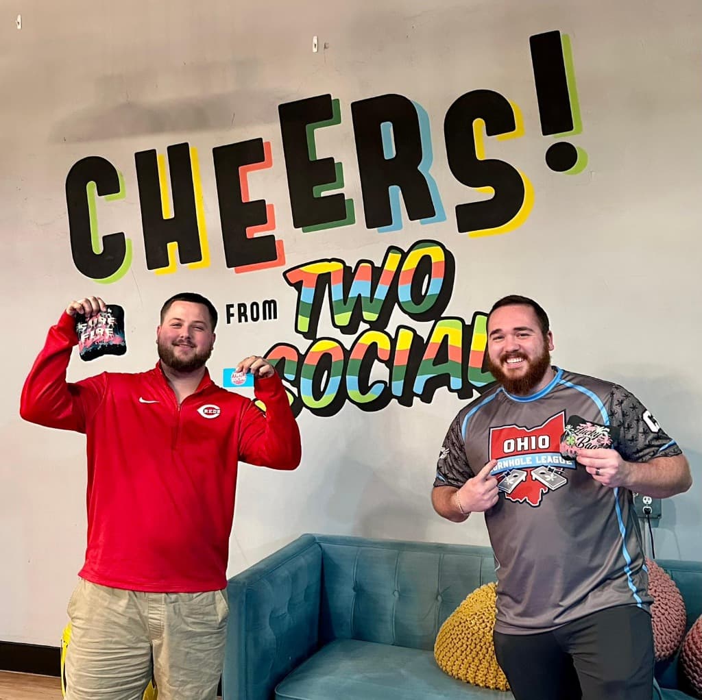 Friends cheering with drinks at downtown Dayton cornhole event