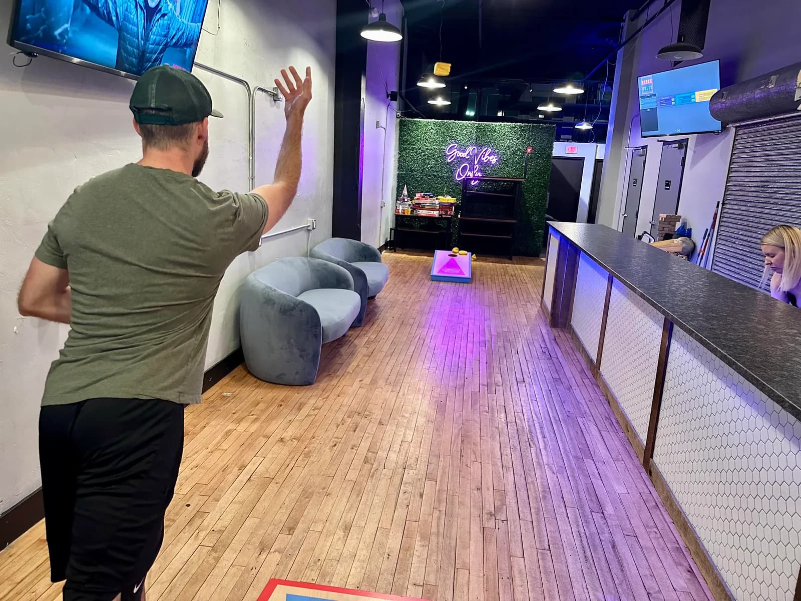 A player tossing a bag toward a cornhole board at Two Social.